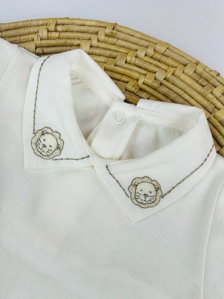 Detalhe da gola do body bebê branco com bordado de leão delicado e acabamento artesanal – Maria Chica Bebê
