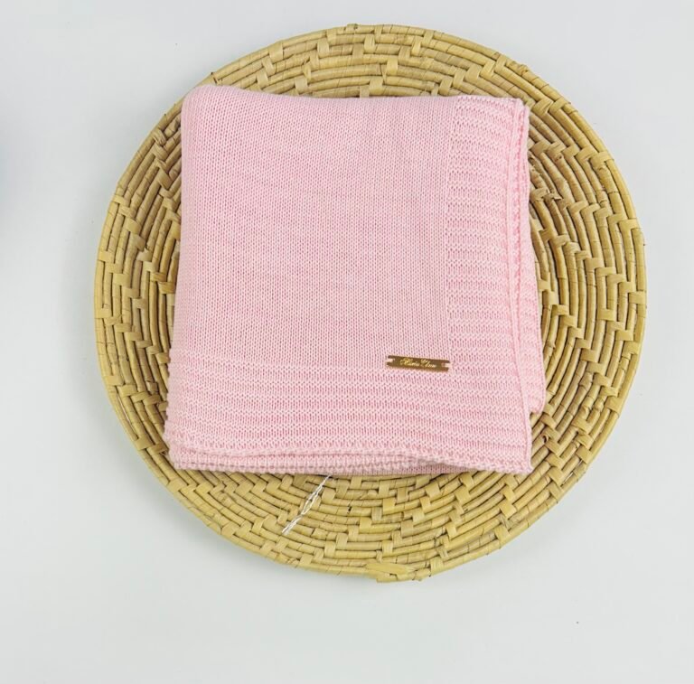 Detalhe da manta unissex para bebê em tricô rosa com acabamento delicado e placa da marca, toque macio e sofisticado – Maria Chica Bebê